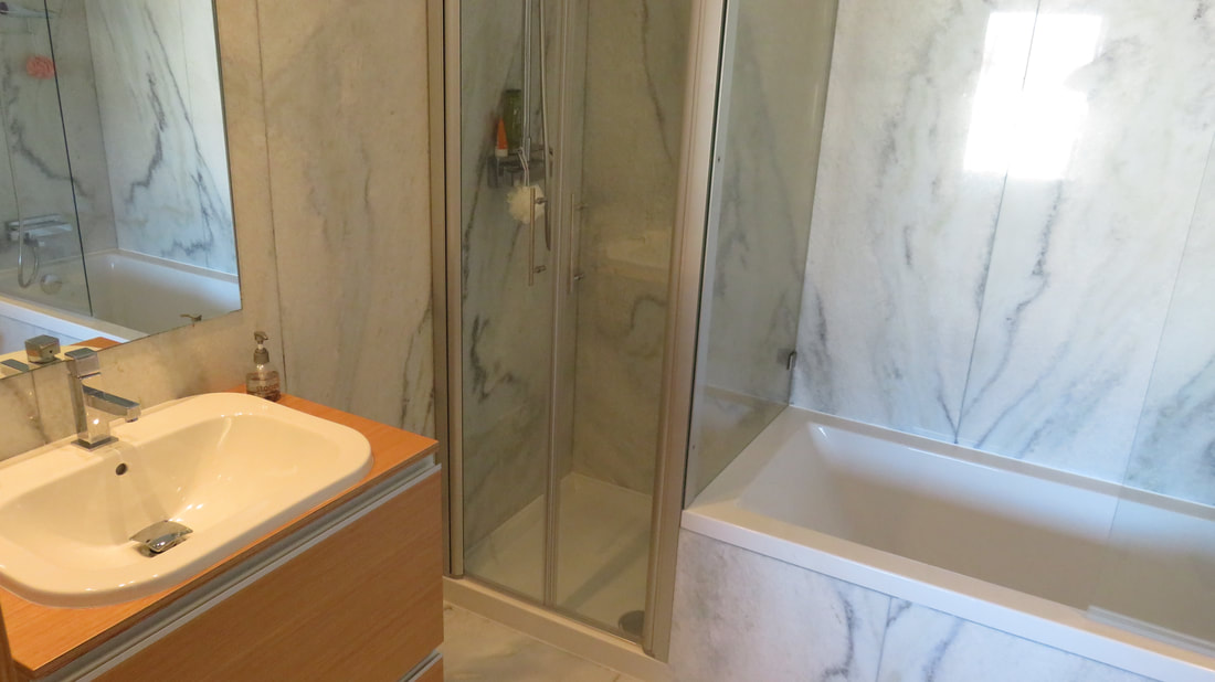 Badkamer in wit marmer met bad en douche